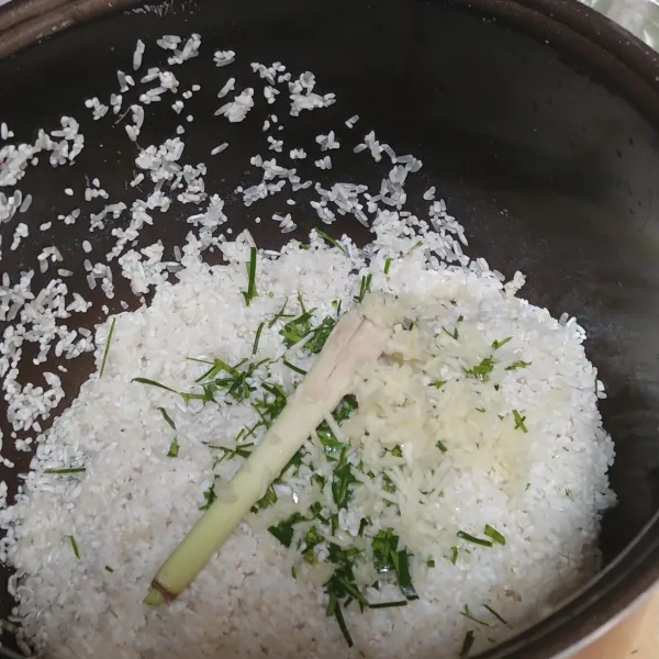 Cuci bersih beras, lalu tambahkan daun jeruk, serai dan bawang putih parut.