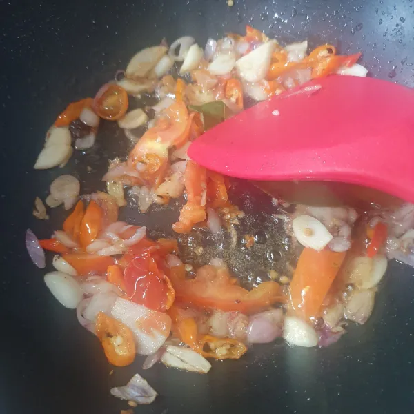Tumis irisan bawang putih, bawang merah, cabe hingga harum. Tambahkan terasi, lengkuas, daun salam dan tomat.