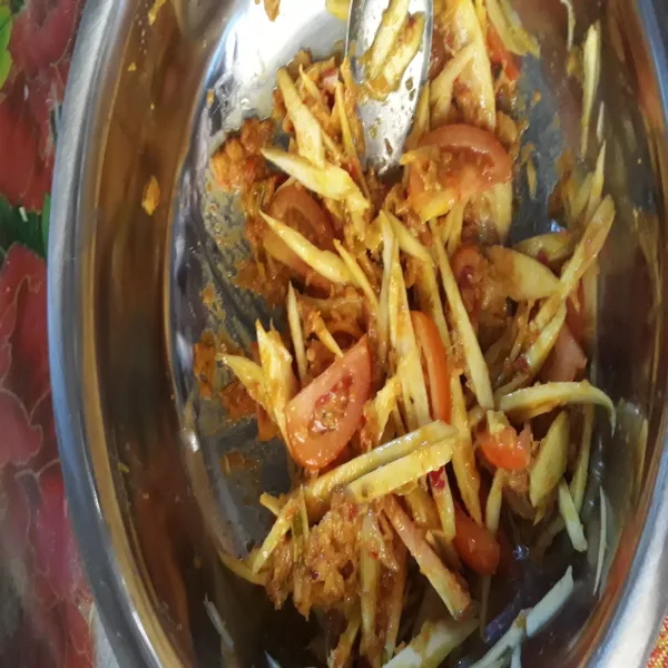 Campur rata bumbu uleg dengan mangga yang telah dicacah dan tomat yang telah dipotong-potong