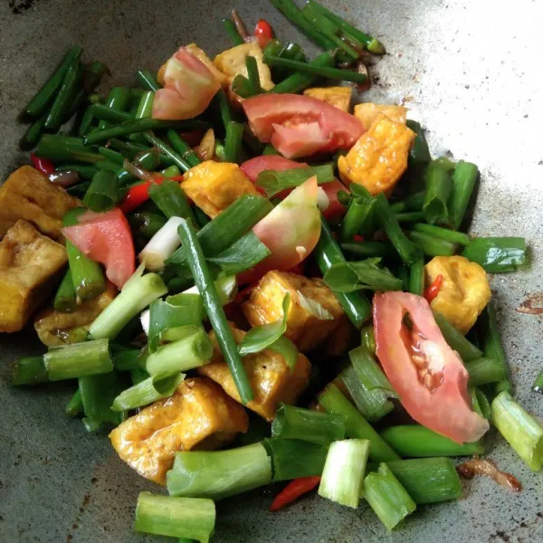 Masukan irisan tomat dan bawang daun, masak hingga bawang daun layu