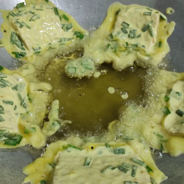 Goreng tempe pada sisi penggorengan, tunggu sampai agak mengeras kemudian geser gorengan ke tengah penggorengan.