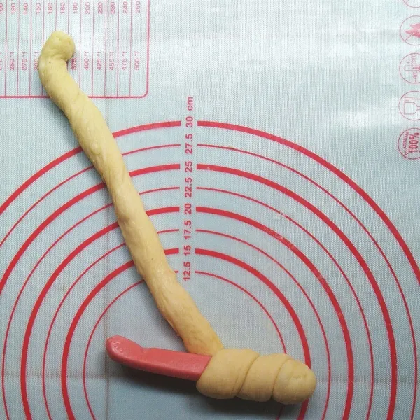 Ambil satu bagian, pilin memanjang menggunakan tangan. Ambil 1 buah sosis, putar dough menutup sosis.