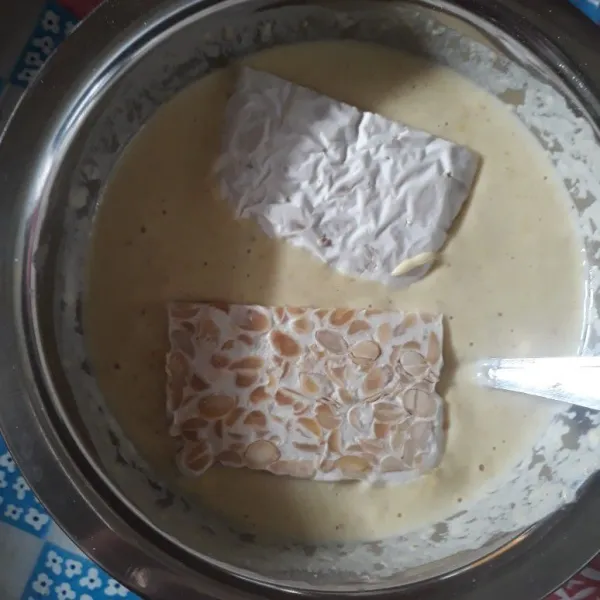 Masukan tempe dalam adonan tepung, aduk-aduk hingga tempe terlumuri tepung.