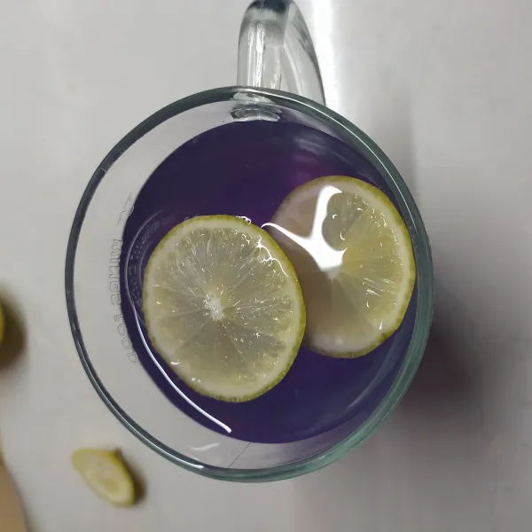 Beri 2 irisan lemon, aduk sebentar. Warna akan perlahan berubah jadi ungu. Sajikan hangat.