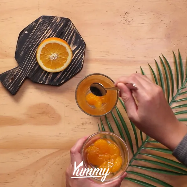 Siapkan gelas saji, masukkan jeruk mandarin dan leci.