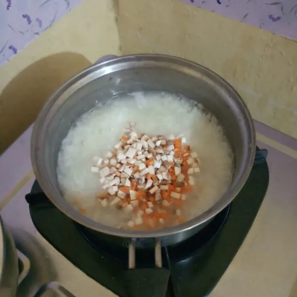 Masukan potongan wortel dan jamur ketika nasi sudah hampir menjadi bubur. Bumbui dengan garam dan kaldu jamur aduk rata.