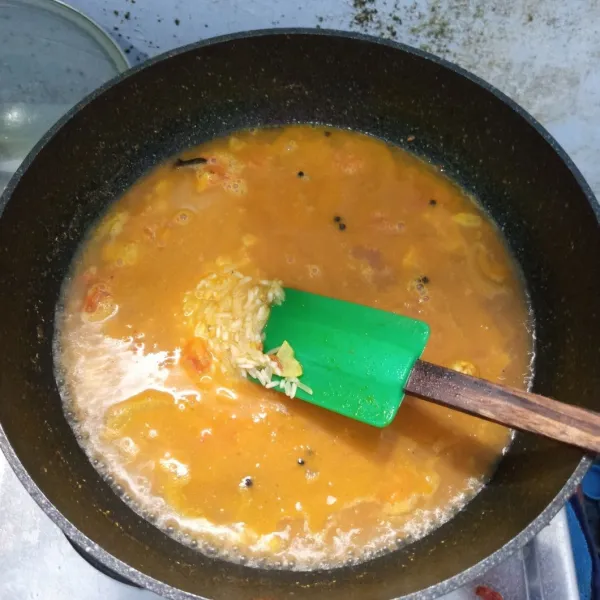 Masukan beras ke dalam air rebusan ayam. Tambahkan air sampai tinggi seruas jari. Kemudian masak sampai air menyusut.