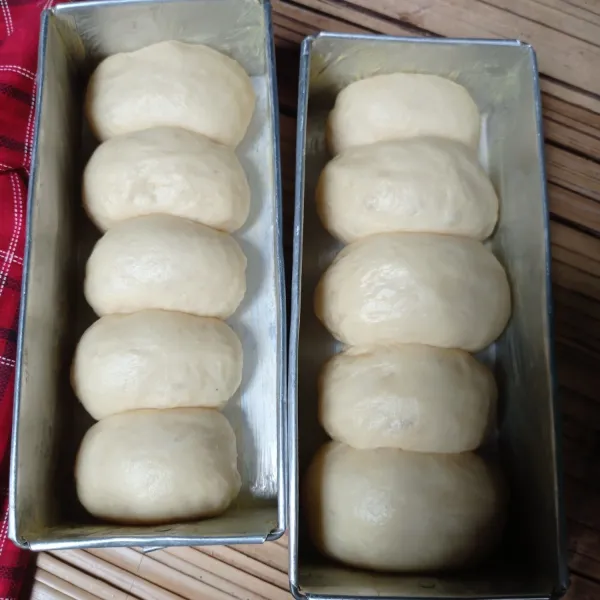 Ambil satu bulatan isi dengan bahan isian, lalu tata dalam loyang yang dioles margarin. Diamkan selama 15 menit, sembari memanaskan otang/oven.