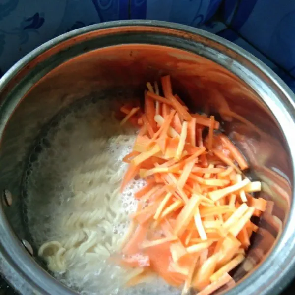 Didihkan air, rebus mie dan irisan wortel hingga setengah matang, tiriskan