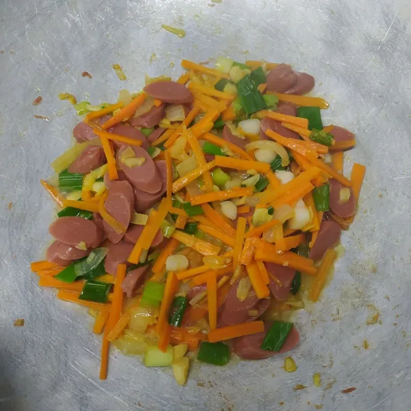 Masukkan wortel, tumis sebentar. Tambahkan sosis, daun bawang dan air. Masak sampai wortel empuk.