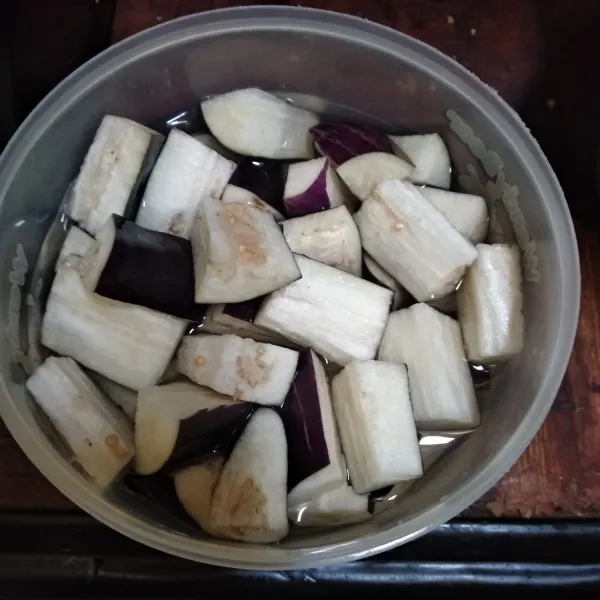 Potong terong, rendam dengan air garam. Lalu bilas dengan air bersih.