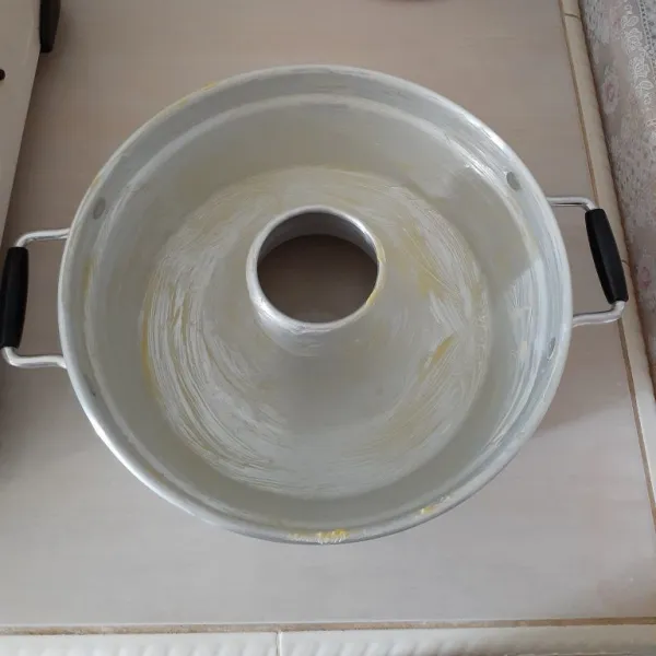Olesi baking pan dengan margarin dan terigu hingga merata.