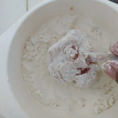Setelah dimarinasi, gulingkan ayam ke dalam tepung terigu.