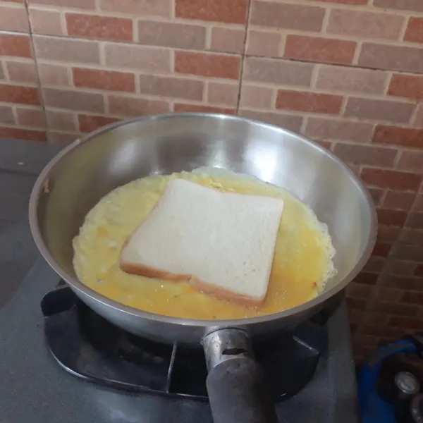 Kocok lepas telur & kaldu bubuk. Dadar setengah telur dengan api kecil. Taruh/ celupkan 1 lembar roti di atas telur.