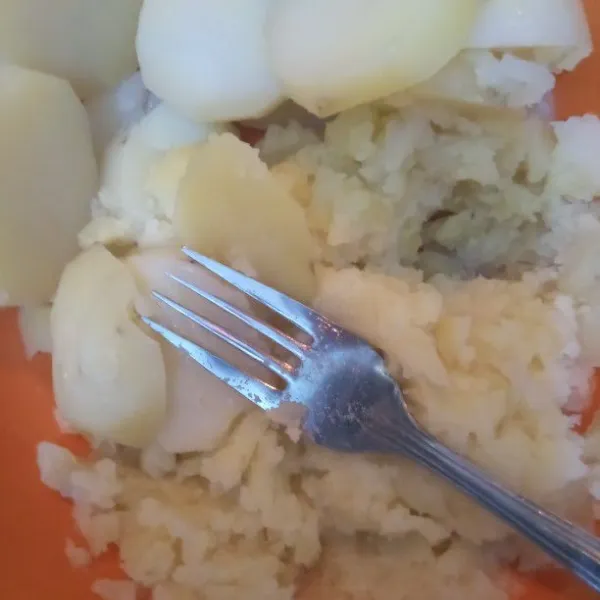 Haluskan kentang menggunakan garpu selagi panas.