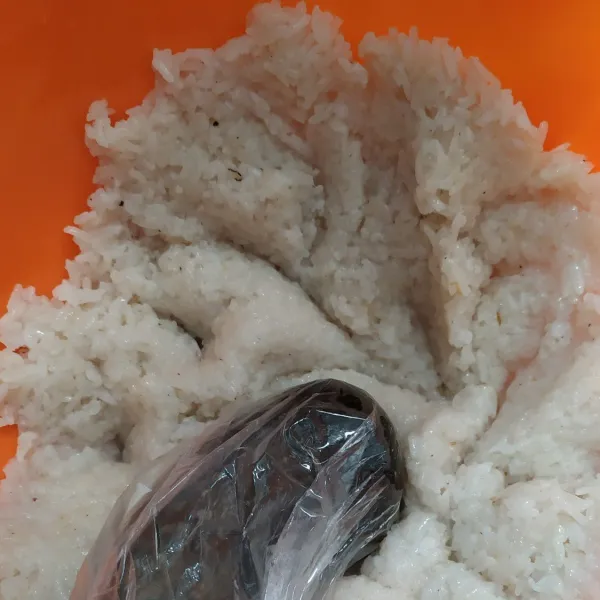 Masukan nasi ketan yang sudah matang ke dalam wadah, tumbuk / haluskan menggunakan ulekan yang dibungkus plastik