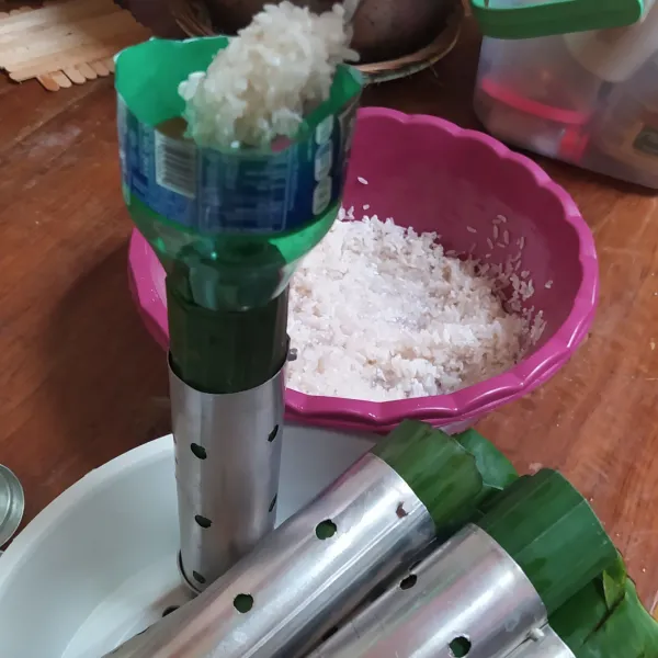Tutup salah satu ujungnya, lalu masukkan beras ke dalam cetakan sebanyak 1/2 tinggi cetakan. Sembari mengisi cetakan, rebus air untuk nanti merebus lontong.