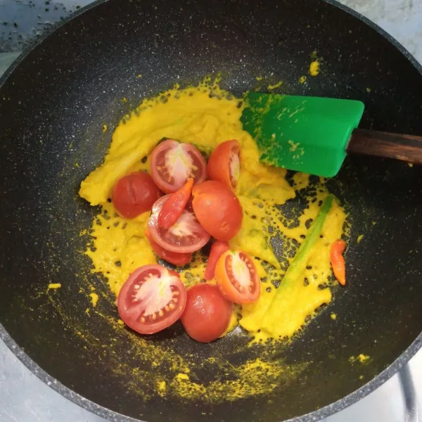 Masukkan tomat dan cabai rawit. Aduk rata. Masak sampai layu.