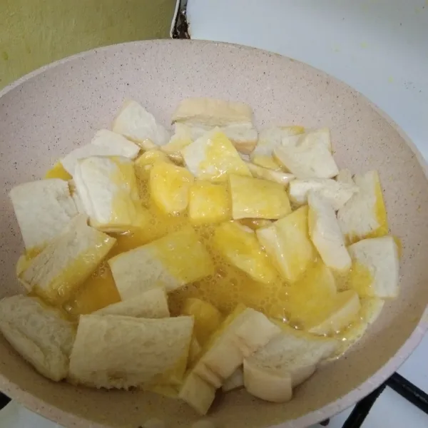 Kocok telur bersama garam, merica dan kaldu jamur, kemudian tuang di atas roti, kecilkan api