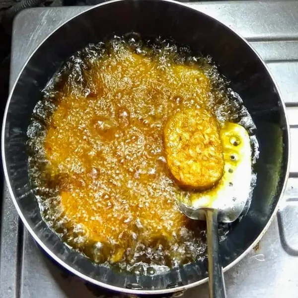 Panaskan minyak, lalu goreng tempe, bolak-balik, tunggu sampai matang berubah warna kuning keemasan