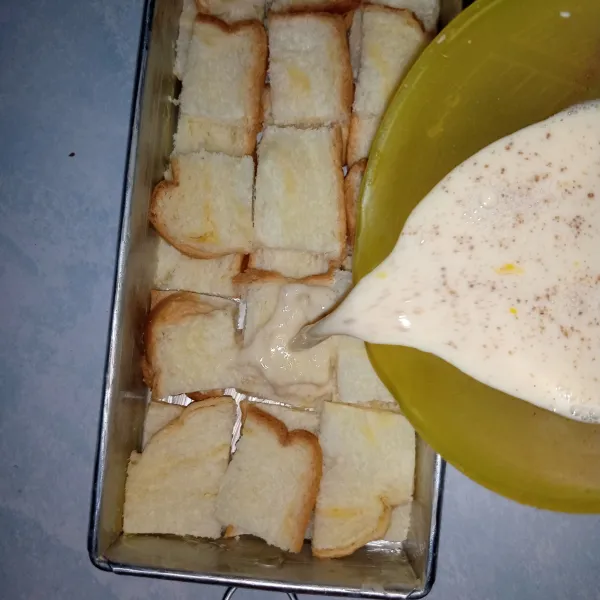 tata roti kedalam loyang yang sudah diolesi butter. kemudian tuang campuran susu.