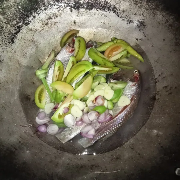Masukan dalam wajan ikan, air, tomat, cabai, belimbing wuluh, serai, bawang merah dan bawang putih.