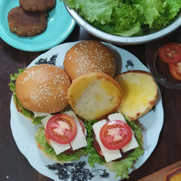 Penyajian: roti, daun selada, daging burger, mayonaise, saos tomat/sambal, timun, keju dan tomat lalu tutup dengan roti
