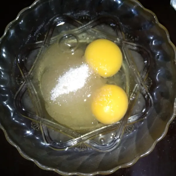 Di tempat yang lain, masukkan 2 butir telur dan 3 sdm gula pasir, lalu kocok sampai gula larut.