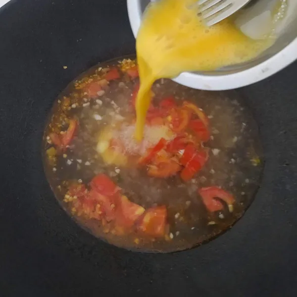 Pecahkan telur ke dalam mangkok, kemudian kocok lepas. Tuang telur ke dalam kuah tomat, aduk cepat.