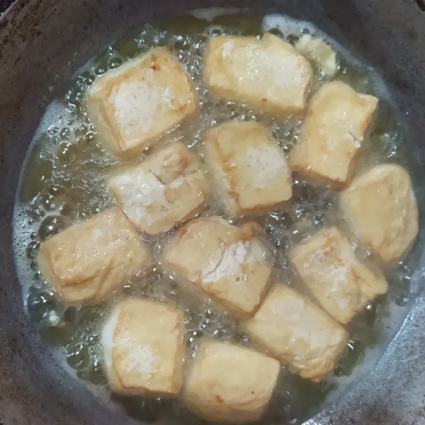 Goreng tahu yang sudah dipotong-potong persegi, setengah matang saja.