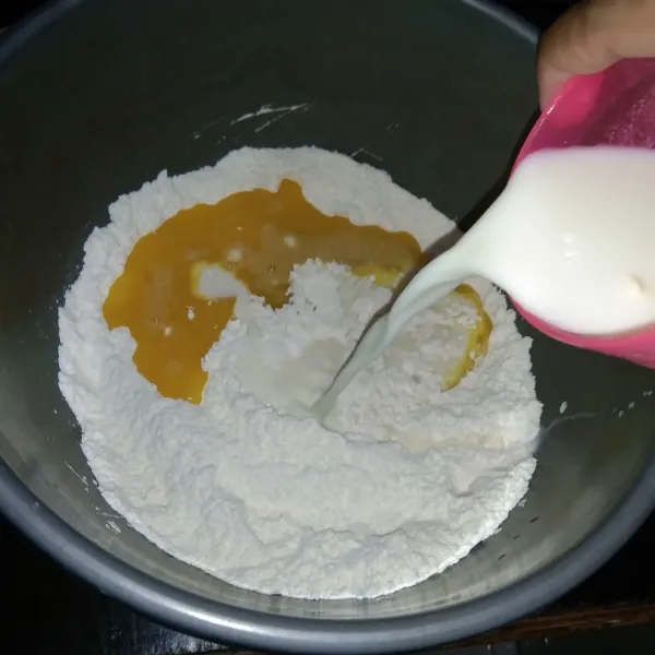 Kemudian, masukkan telur yang sudah dikocok, lalu tambahkan susu cair ke dalam tepung yang tadi dan aduk sampai semua bahan tercampur rata.
