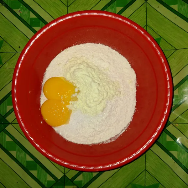 Masukkan tepung terigu, gula pasir, susu bubuk, kuning telur dan baking powder, aduk rata.
