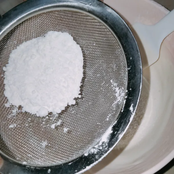 Masukkan tepung terigu sambil diayak sebanyak tiga tahap.