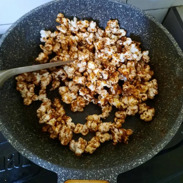Masukan brondong jagung ke dalam wajan berisi karamel, aduk rata.