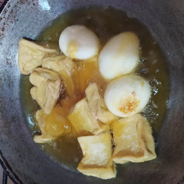 Goreng tahu dan telur rebus sampai berkulit, lalu tiriskan.