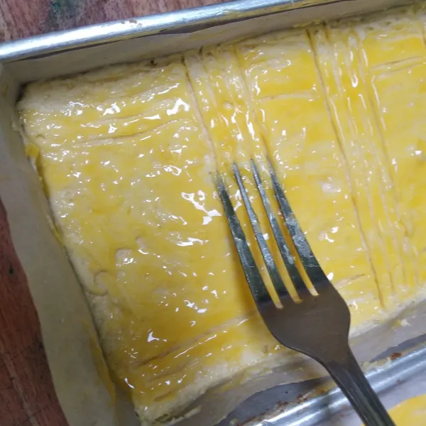 Ratakan kemudian oles dengan kuning telur, buat motifnya menggunakan sendok garpu.