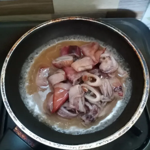 Masukkan cumi dan larutan asam ke panci. Masak sampai air menyusut.