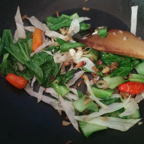 Tumis bawang putih cincang hingga harum, tambahkan sawi, kol, cabe rawit dan minyak sayur.
