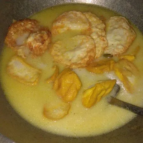 Masukkan air dan santan masak sampai mendidih lalu masukkan telur coplok dan tahu goreng.