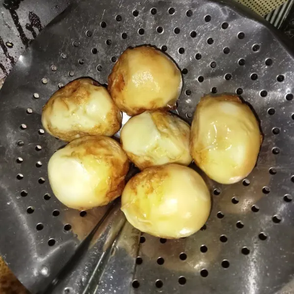 Rebus telur hingga matang dan kupas kulitnya. Lalu goreng telur hingga berkulit, tiriskan.
