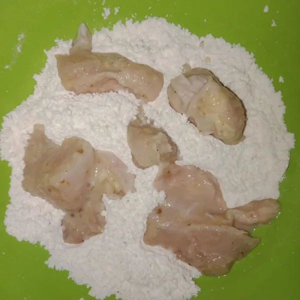 Siapkan tepung terigu lalu masukkan satu persatu daging ayam, guling-gulingkan ayam hingga terbalur semua tepung.