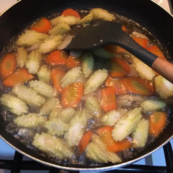 Masukkan jagung manis dan wortel. Kemudian tambahkan air.