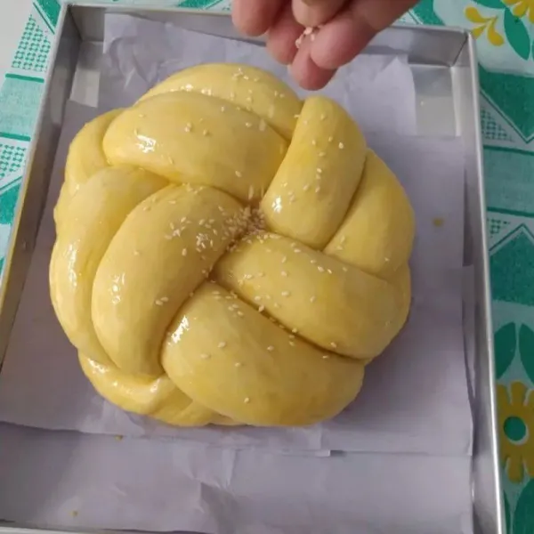 Diamkan roti yang sudah dikepang sampai mengembang 2x lipat. Kemudian olesi dengan sisa kuning telur, taburi dengan wijen.