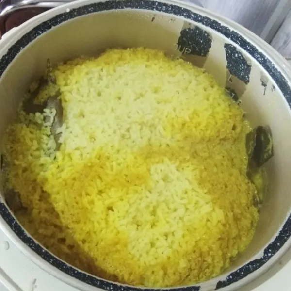 Ketika nasi kuning matang (magicom berpindah ke tombol warm). Buka magicomnya lalu aduk rata nasinya (karena bumbu akan berada di permukaan nasi).
