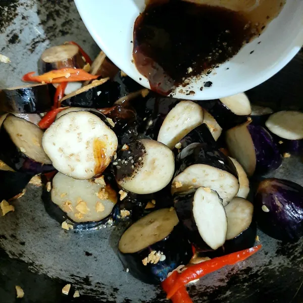 Masukkan saus tiram, kecap manis, saus tomat, minyak wijen, garam, dan lada hitam. Aduk rata. Masukkan air, masak selama 5 menit sampai terong matang. Koreksi rasa.