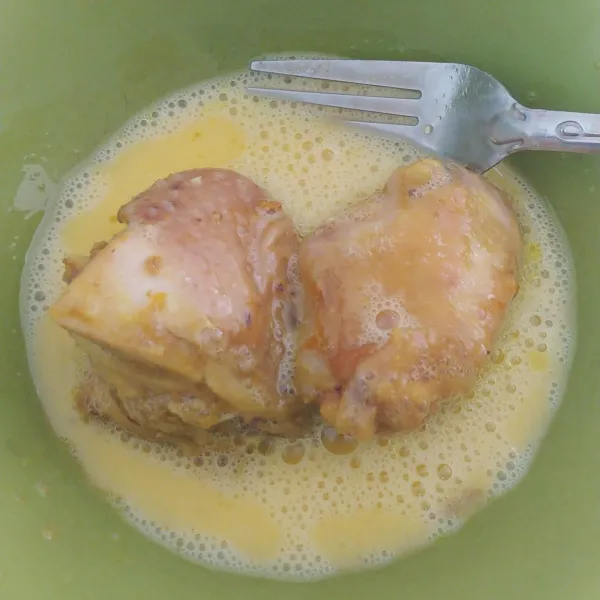 Kocok telur dalam mangkok lalu masukkan beberapa potong ayam ungkep.