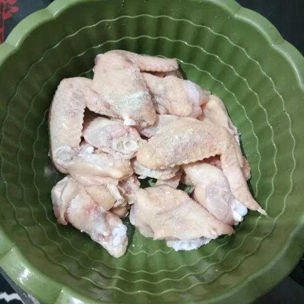 Potong sayap ayam menjadi 2 bagian, lalu cuci bersih dan beri bumbu marinasi, aduk rata, diamkan selama 15 menit.