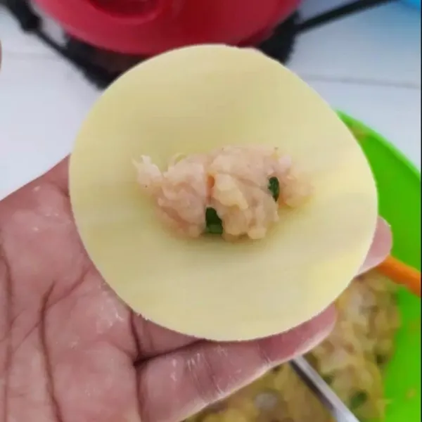 Bentuk bulat kulit pangsit, kemudian isi dengan adonan ayam.