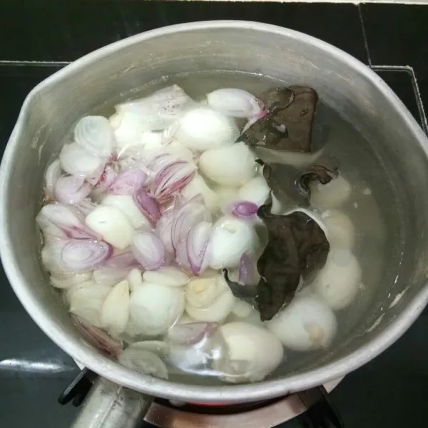 Masukkan telur puyuh, bawang merah, bawang putih, daun salam dan lengkuas ke dalam panci. Masak hingga mendidih.