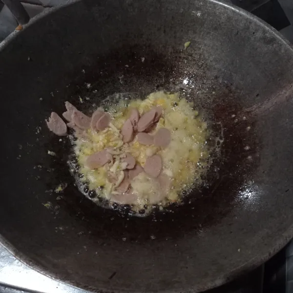 Masak telur orak arik setengah matang. Masukkan cincangan bawang putih dan irisan sosis. Aduk rata.